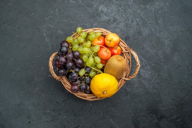 Vista superior de la composición de diferentes frutas frescas y maduras dentro de la canasta sobre el fondo gris oscuro suaves frutas frescas salud madura