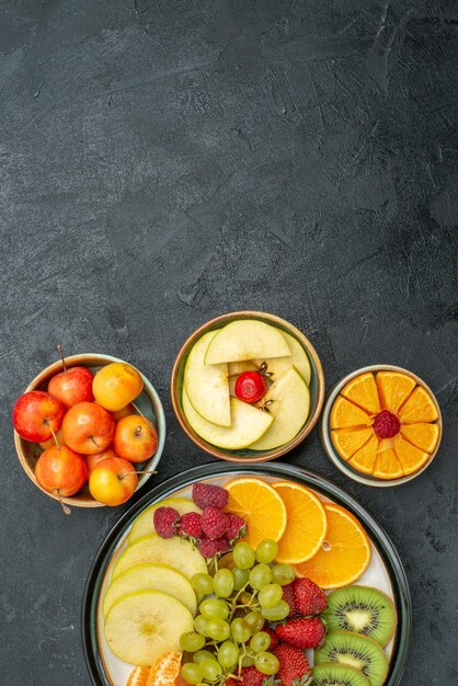 Vista superior de la composición de diferentes frutas frutas frescas suaves y en rodajas en el escritorio oscuro frutas frescas salud suave madura