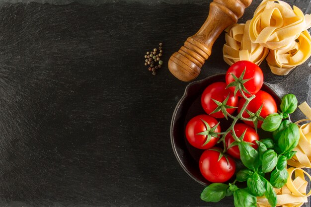 Vista superior de composición fantástica con albahaca, pasta y tomates