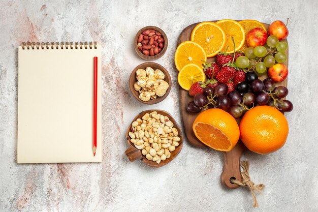 Vista superior de la composición de fruta fresca naranjas frescas uvas nueces y fresas sobre superficie blanca