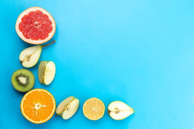 Una vista superior de la composición de fruta fresca en rodajas suave y madura en azul, vitamina de color de fruta