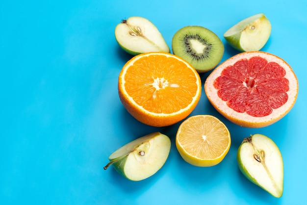 Una vista superior de la composición de frutas coloridas en rodajas frutas frescas y suaves en azul, imagen en color de frutas