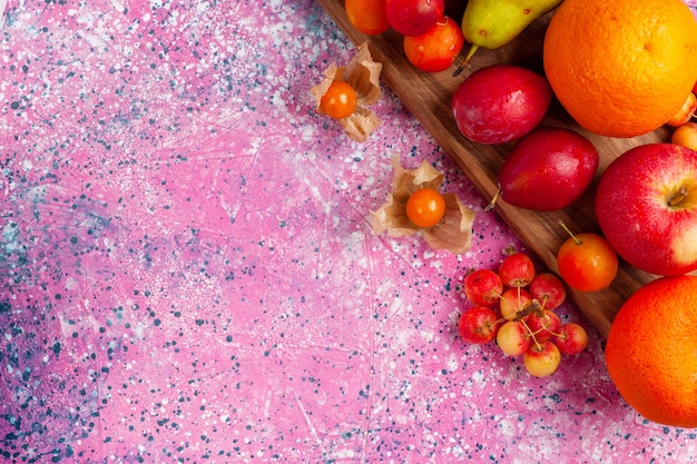 Vista superior de la composición de frutas diferentes frutas frescas y suaves sobre fondo rosa.