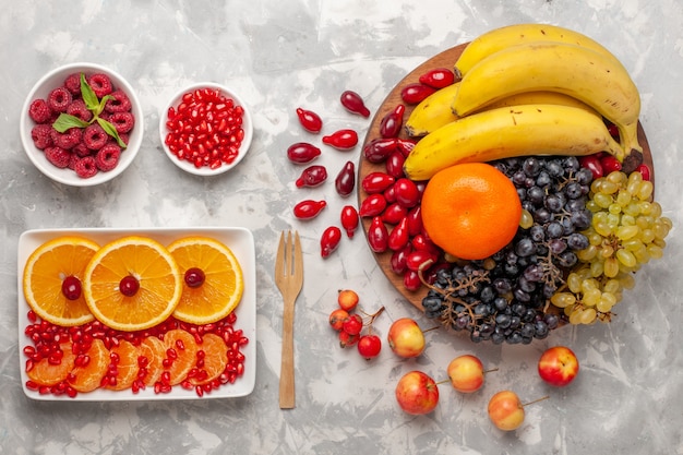 Foto gratuita vista superior de la composición de frutas frescas, cornejos, uvas, plátanos y naranjas sobre superficie blanca, jugo de vitamina, vitamina suave.