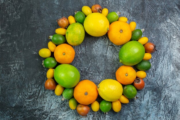 Vista superior de la composición de frutas frescas limones feijoa y mandarinas sobre fondo gris