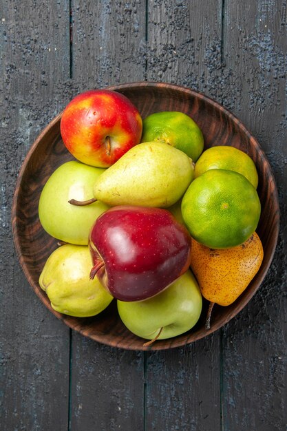 Vista superior de la composición de frutas frescas manzanas, peras y mandarinas dentro de la placa en el escritorio azul oscuro color de la fruta árbol meloso maduro fresco