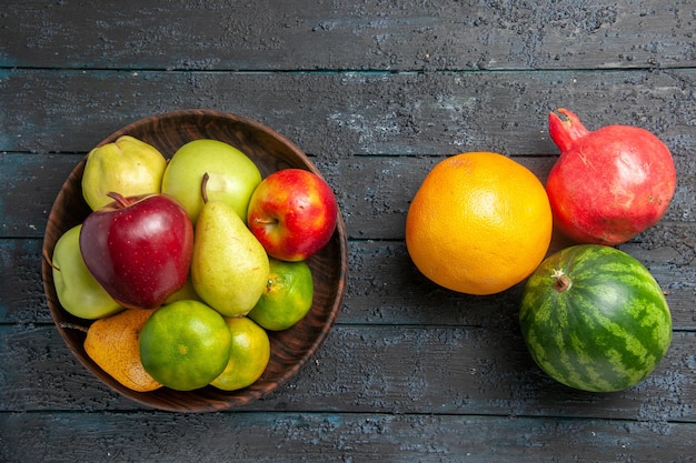 Vista superior de la composición de frutas frescas manzanas, peras y mandarinas en el escritorio de color azul oscuro, fruta madura, color fresco, meloso