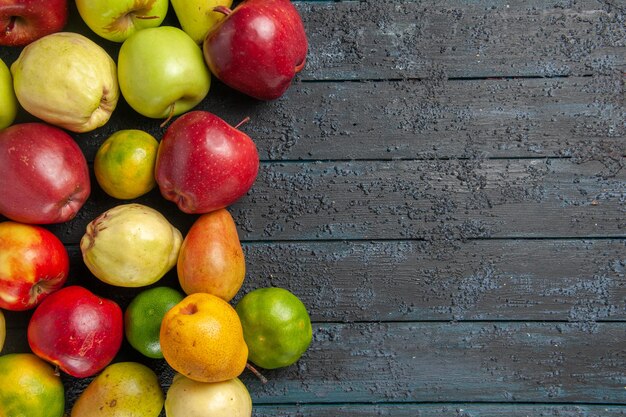 Vista superior de la composición de frutas frescas manzanas, peras y mandarinas en el escritorio de color azul oscuro frutas maduras de color meloso muchos frescos