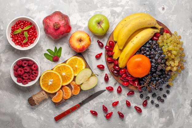 Vista superior de la composición de frutas frescas, plátanos, cornejos y uvas en la superficie de color blanco claro, frutas, bayas, frescura, vitamina