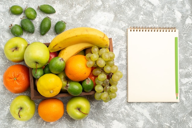 Vista superior de la composición de frutas frescas, plátanos, uvas y feijoa sobre fondo blanco, frutas, vitamina suave, salud, madura fresca.