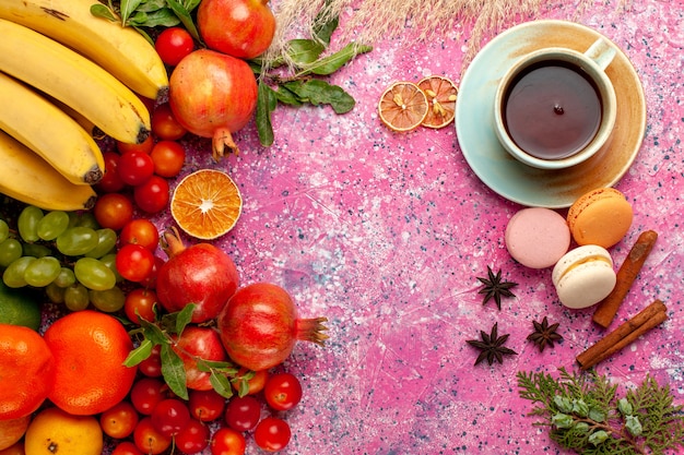 Vista superior de la composición de frutas frescas con una taza de té en la superficie de color rosa claro