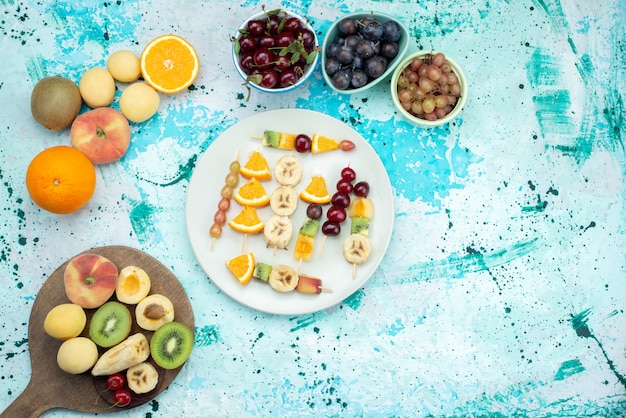 Vista superior de la composición de frutas en rodajas y enteras en el escritorio azul fruta exótica galleta azúcar