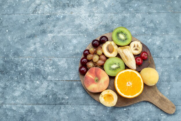 Vista superior de la composición de frutas en rodajas y enteras en el escritorio azul fruta exótica galleta azúcar