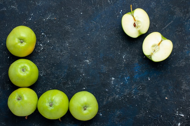 Vista superior de la composición de manzanas verdes frescas con rodajas forradas en un escritorio oscuro, fruta fresca madura suave