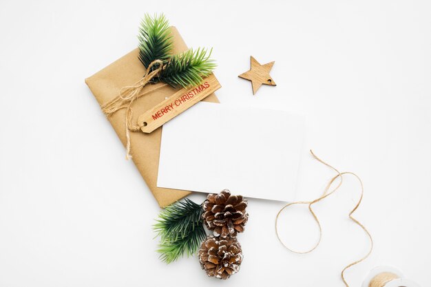Vista superior de la composición navideña con caja de regalo, cinta, ramas de abeto, conos, anís en mesa blanca