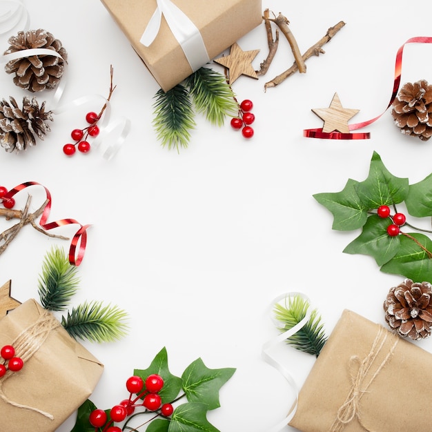 Vista superior de la composición navideña con caja de regalo, cinta, ramas de abeto, conos, anís en mesa blanca