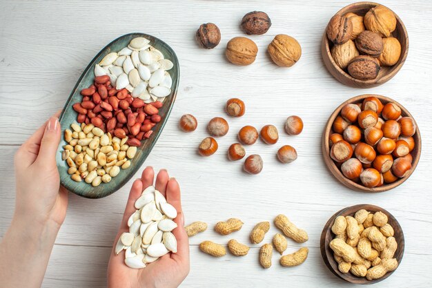 Vista superior de la composición de nueces cacahuetes semillas avellanas y nueces en mesa blanca