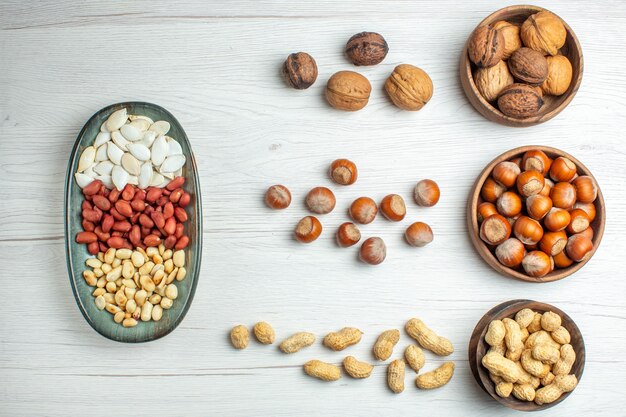 Vista superior de la composición de nueces cacahuetes semillas avellanas y nueces en mesa blanca