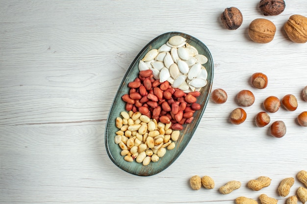 Vista superior de la composición de nueces cacahuetes semillas avellanas y nueces en mesa blanca