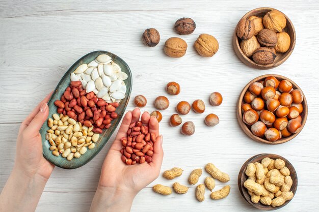 Vista superior composición de nueces semillas de cacahuetes avellanas y nueces en planta de bocadillos de pistachos de nuez de mesa blanca