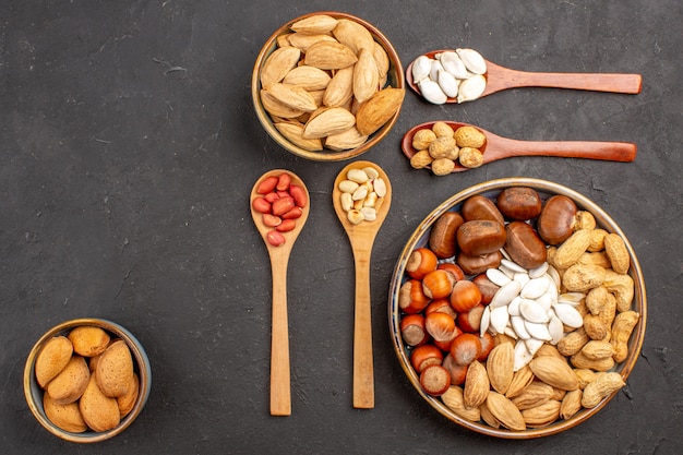 Foto gratuita vista superior de la composición de la nuez con diferentes nueces en la superficie oscura