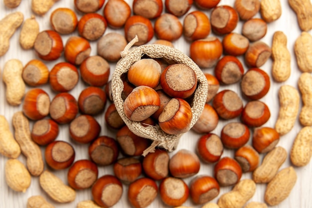 Vista superior de la composición de la tuerca avellanas frescas y cacahuetes en la nuez de maní de aperitivo de nuez de escritorio blanco