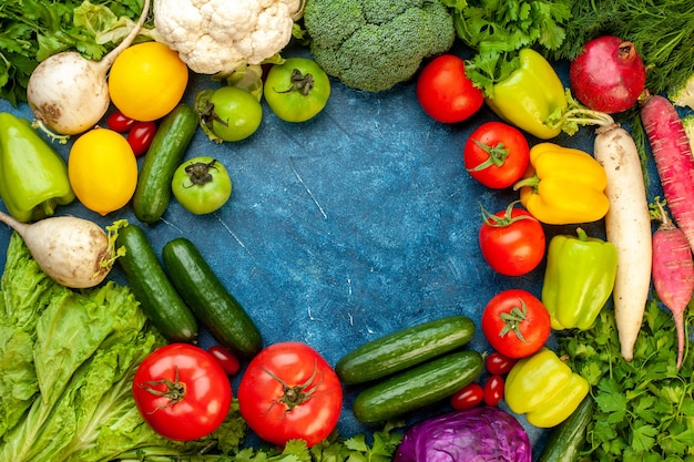 Vista superior de la composición vegetal con frutas frescas en el escritorio azul, ensalada de dieta, vida sana, color maduro