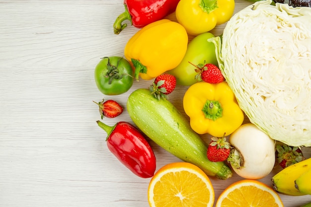 Vista superior de la composición de verduras frescas con frutas sobre fondo blanco.