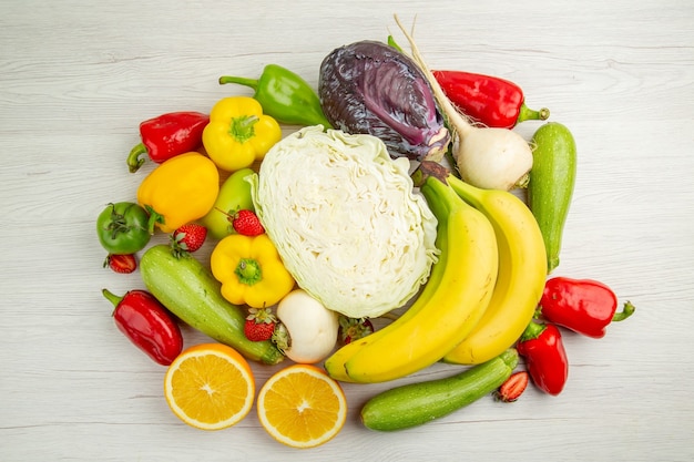 Vista superior de la composición de verduras frescas con frutas sobre fondo blanco.