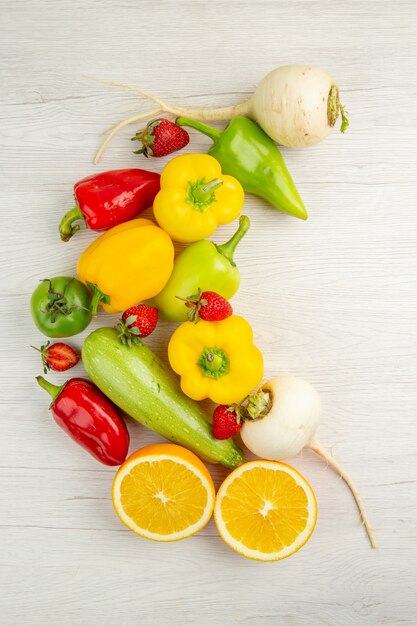 Vista superior de la composición de verduras frescas con frutas sobre fondo blanco.