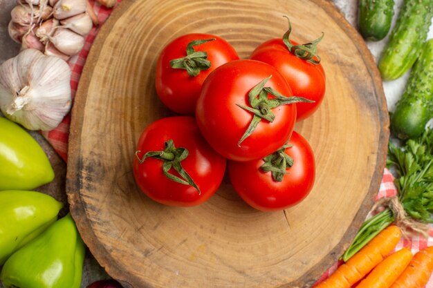 Vista superior de la composición de verduras frescas con tomates sobre fondo blanco.
