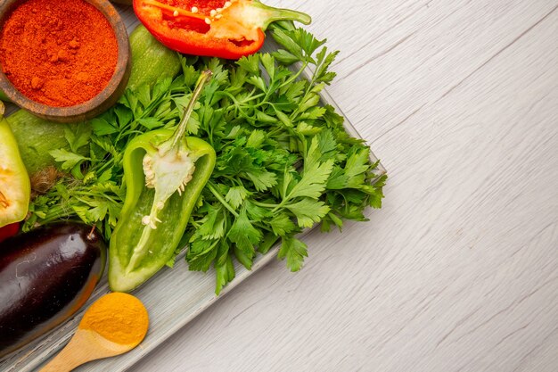 Vista superior de la composición de verduras frescas con verduras y condimentos en la mesa blanca