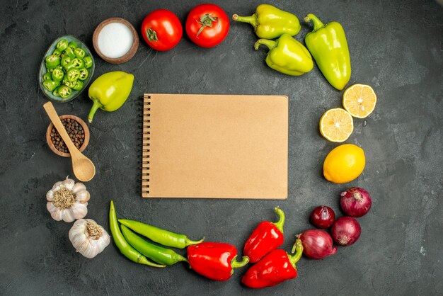 Vista superior de la composición de verduras tomates pimientos y ajos sobre fondo oscuro