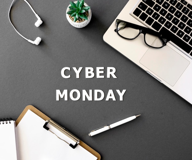 Vista superior de la computadora portátil con bloc de notas y planta para cyber monday