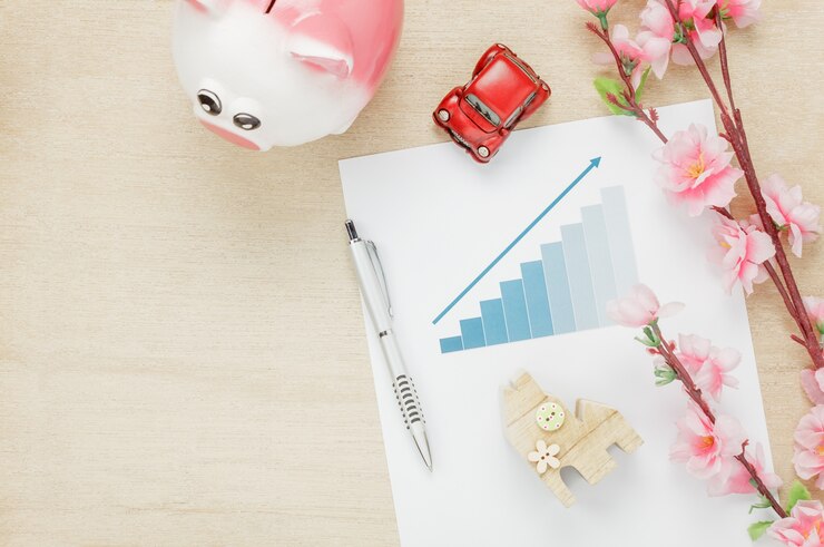 Foto gratuito vista superior concepto de escritorio de oficina de negocios. ahorro de dinero con el resumen gráfico casa de madera también coche y reloj en estante de madera. la hermosa flor rosa con lápiz sobre fondo de madera con copia espacio.