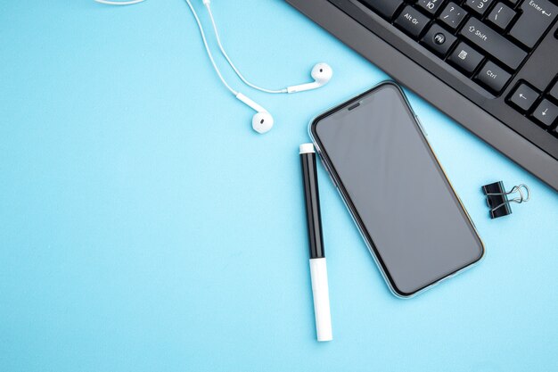 Vista superior del concepto de oficina con auriculares de teléfono móvil en superficie azul