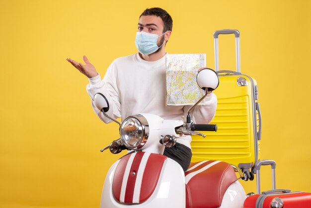 Vista superior del concepto de viaje con chico joven en máscara médica de pie cerca de motocicleta con maleta amarilla