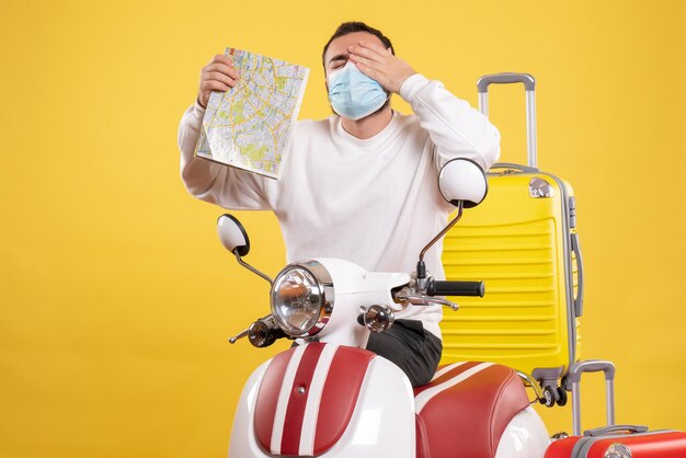 Vista superior del concepto de viaje con chico joven en máscara médica de pie cerca de motocicleta con maleta amarilla