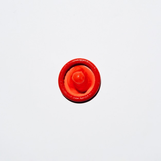 Vista superior del condón rojo sobre fondo blanco.
