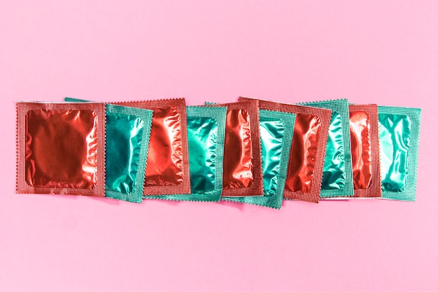 Vista superior de condones en envoltorios rojos y verdes.
