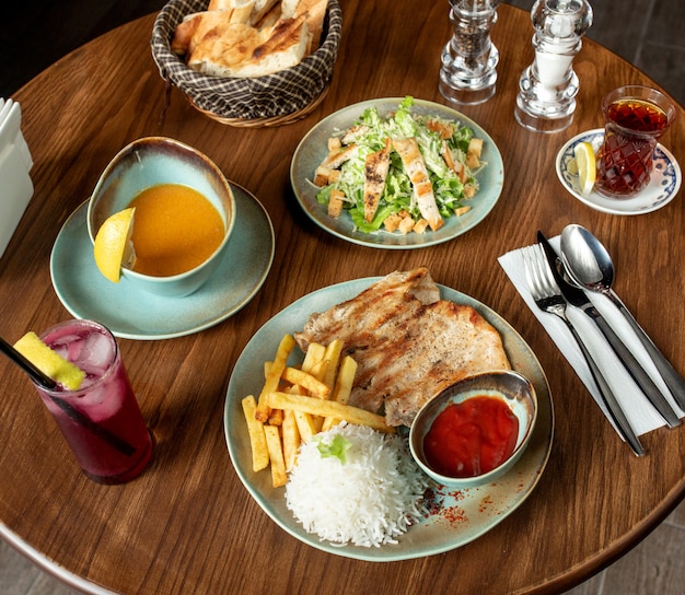 Vista superior de la configuración del almuerzo con pollo a la parrilla y sopa de lentejas de arroz y ensalada