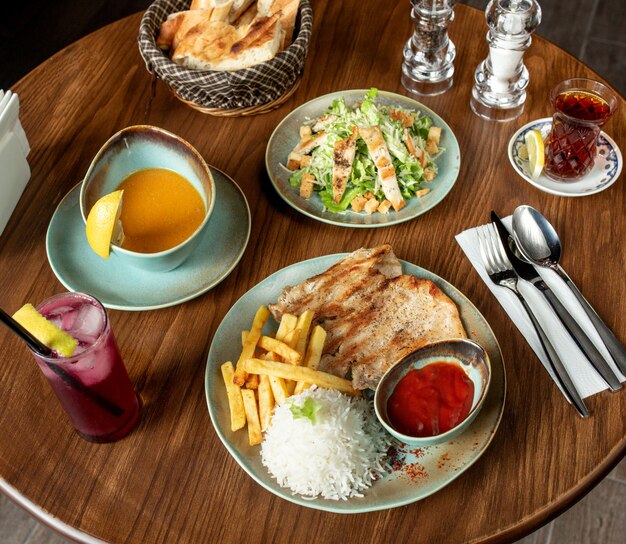 Vista superior de la configuración del almuerzo con pollo a la parrilla y sopa de lentejas de arroz y ensalada