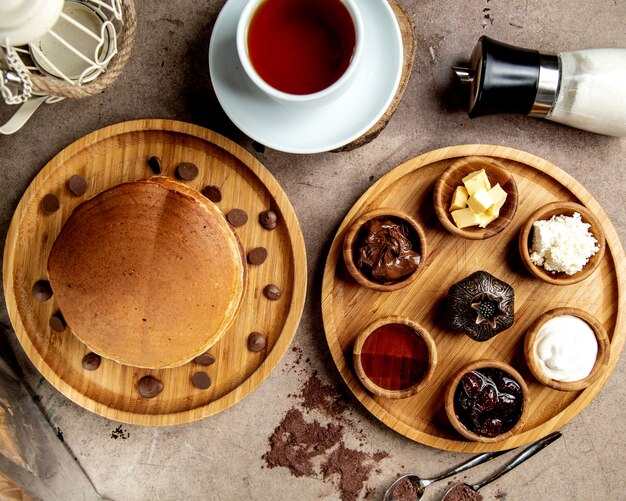 Vista superior de la configuración del desayuno con panqueques, mermeladas, queso, crema y mantequilla de chocolate