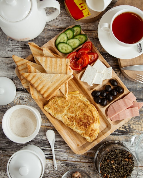 Vista superior de la configuración del desayuno con tortilla tostada pepino tomate queso oliva