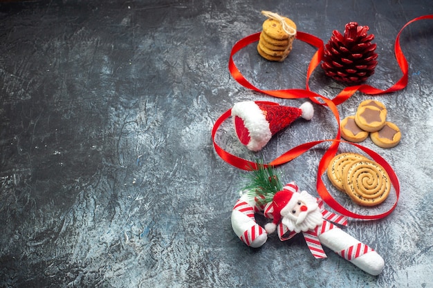 Vista superior del cono de conífera roja del sombrero de santa claus y varias galletas galletas en el lado izquierdo sobre una superficie oscura