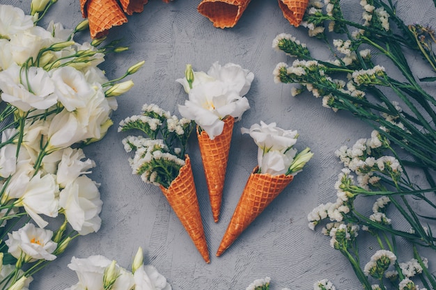 Vista superior de conos de helado con flores en gris claro