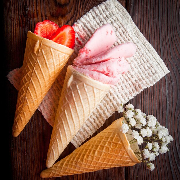Vista superior conos de waffle con fresa y helado y gypsophila en servilletas de trapo
