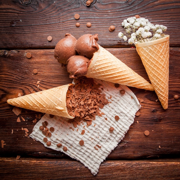 Vista superior conos de waffle con helado de chocolate y gypsophila y chips de chocolate en servilletas de trapo