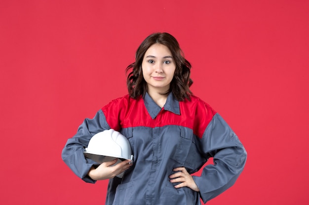 Foto gratuita vista superior de la constructora confiada en uniforme y sosteniendo el casco sobre fondo rojo aislado