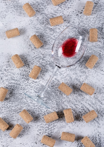 Vista superior de copa de vino con tapones de corcho en piedra blanca vertical